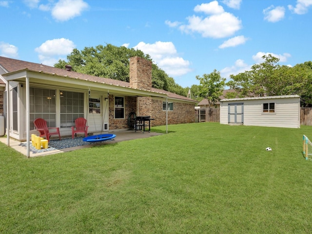 rear view of house with a chimney, fence, an outbuilding, a patio area, and a lawn