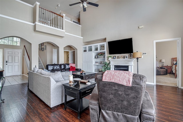 living room featuring arched walkways, a high ceiling, hardwood / wood-style flooring, and a fireplace