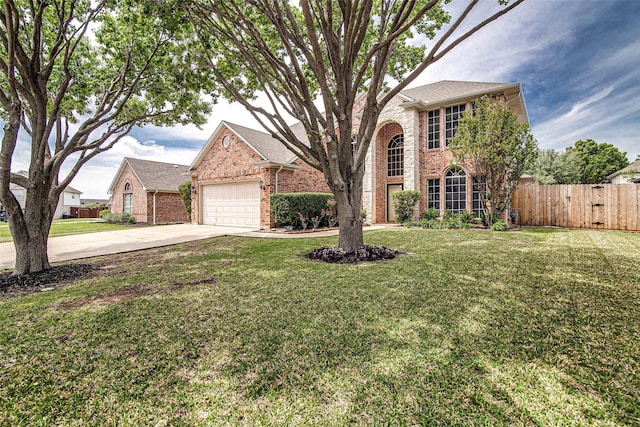 traditional-style house with fence, concrete driveway, brick siding, a front yard, and a garage