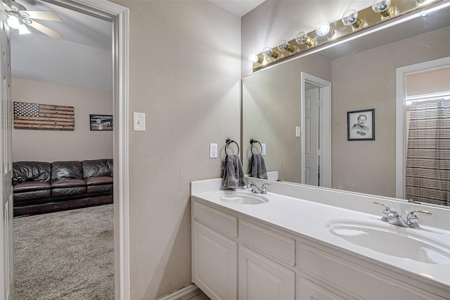 full bathroom featuring double vanity, a textured wall, a sink, and ceiling fan