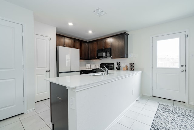 kitchen with dark brown cabinets, visible vents, light tile patterned floors, and black appliances