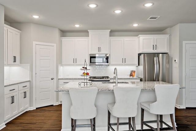 kitchen featuring decorative backsplash, white cabinetry, appliances with stainless steel finishes, dark wood-type flooring, and visible vents