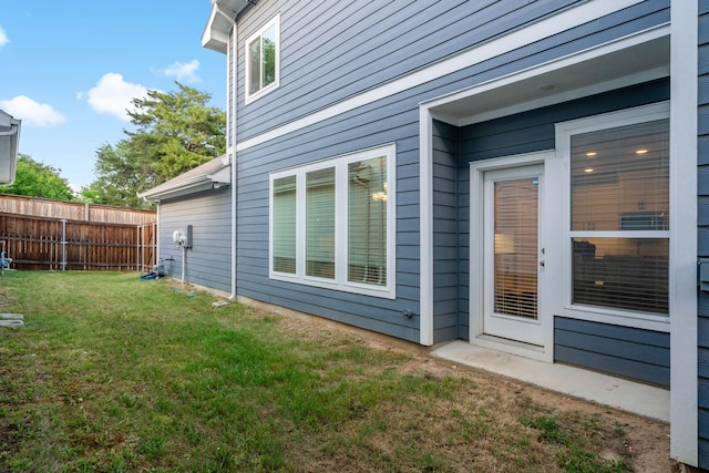 view of side of home with a lawn and fence