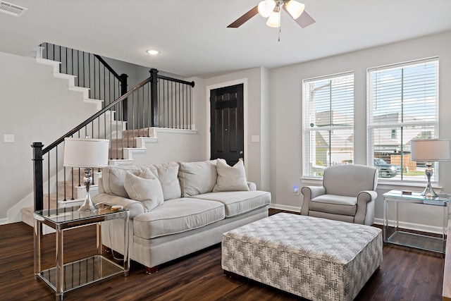 living room with dark wood finished floors, baseboards, visible vents, stairs, and ceiling fan