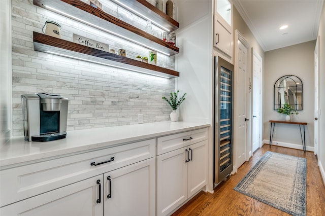 bar with tasteful backsplash, baseboards, light wood-style floors, beverage cooler, and ornamental molding