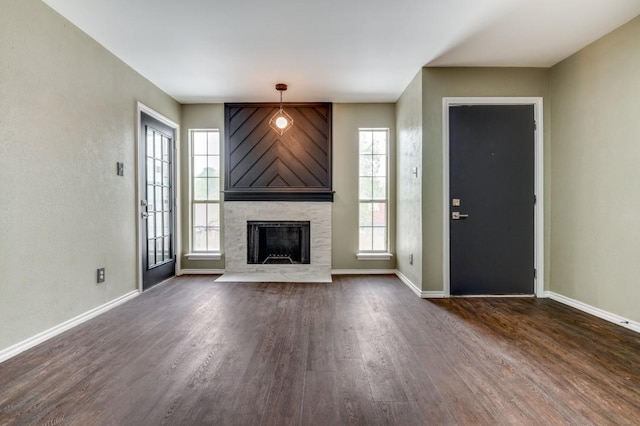 unfurnished living room featuring dark wood-type flooring, a large fireplace, and baseboards