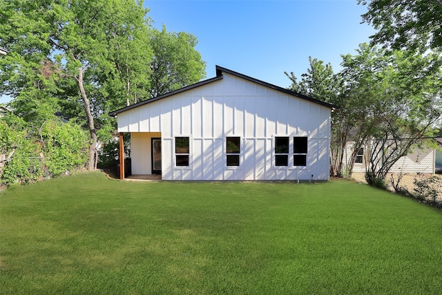 rear view of property featuring board and batten siding and a yard
