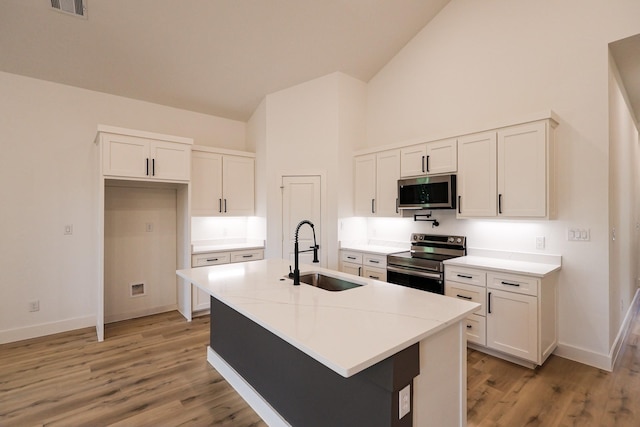kitchen with high vaulted ceiling, white cabinets, appliances with stainless steel finishes, and a sink