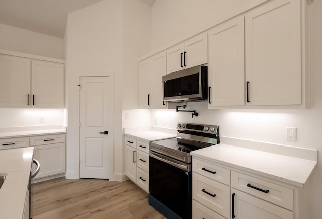 kitchen featuring stainless steel appliances, light wood-style floors, and white cabinetry