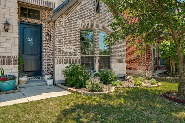doorway to property featuring a lawn and brick siding