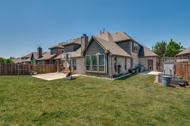 back of house with a fenced backyard, brick siding, a patio, and a lawn