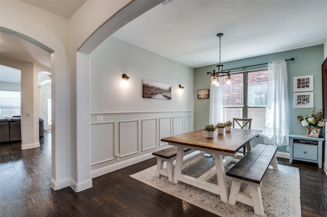 dining room with arched walkways, dark wood finished floors, a healthy amount of sunlight, and a chandelier