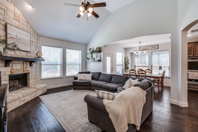 living area with high vaulted ceiling, a ceiling fan, arched walkways, a wealth of natural light, and baseboards