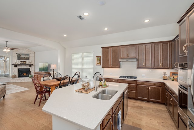 kitchen with a fireplace, plenty of natural light, a ceiling fan, and a sink