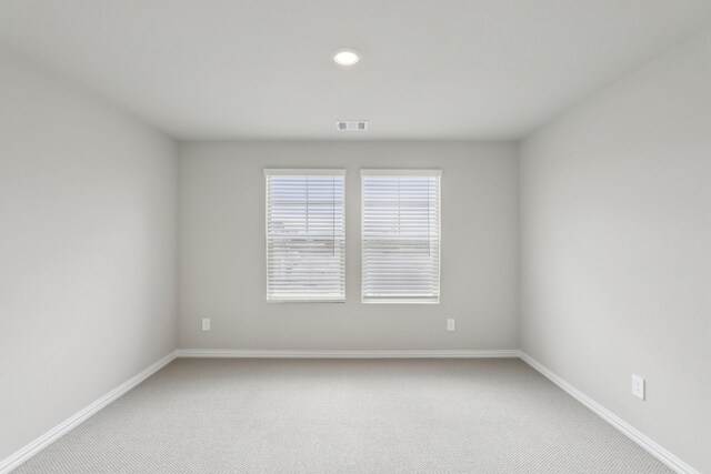 spare room featuring visible vents, baseboards, recessed lighting, and light colored carpet