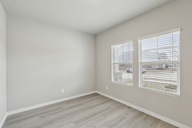 empty room featuring baseboards and light wood finished floors