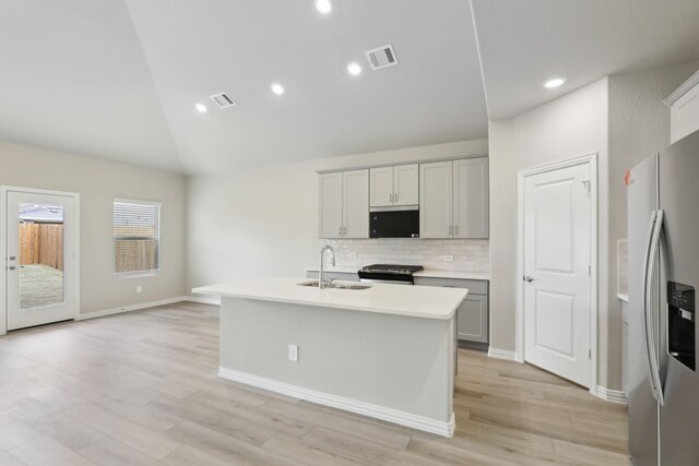 607 Ezra Ln, Mckinney, TX 75069 - kitchen with stainless steel fridge with ice dispenser, decorative backsplash, black range with gas stovetop, a kitchen island with sink, and light countertops