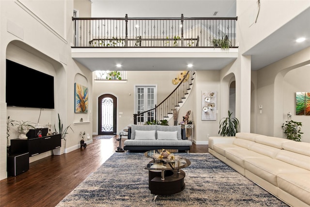 13043 Seattle Slew St, Frisco, TX 75035 - living room featuring wood finished floors, a towering ceiling, baseboards, arched walkways, and stairway