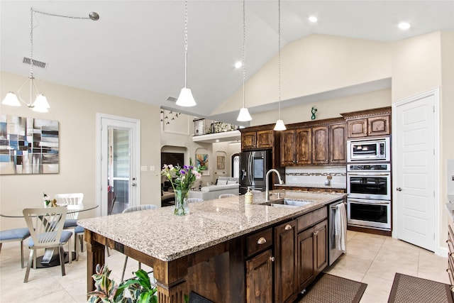 13043 Seattle Slew St, Frisco, TX 75035 - kitchen featuring appliances with stainless steel finishes, a sink, an island with sink, dark brown cabinetry, and light tile patterned floors
