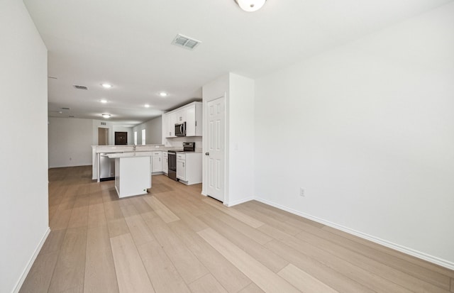 1055 Clear Dusk Ln, Forney, TX 75126 - kitchen featuring stainless steel appliances, open floor plan, light wood-type flooring, a center island, and white cabinets