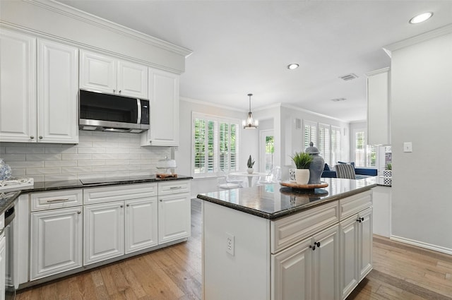 1102 Belvedere Dr, Allen, TX 75013 - kitchen with white cabinetry, light wood-style flooring, stainless steel microwave, backsplash, and ornamental molding