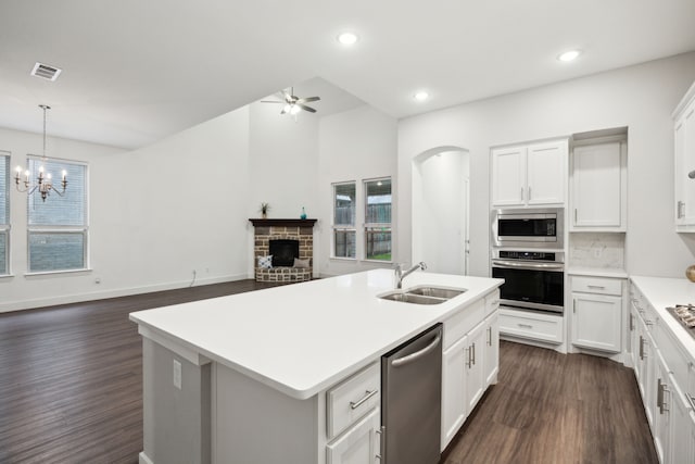 kitchen featuring visible vents, dark wood-style flooring, a brick fireplace, a sink, and stainless steel appliances