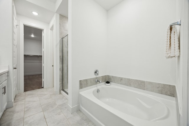 bathroom with a walk in closet, a bath, a shower stall, vanity, and recessed lighting