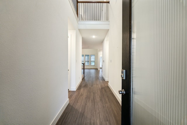 corridor featuring baseboards and dark wood-type flooring