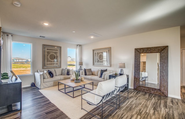 living room with baseboards, visible vents, a wealth of natural light, and dark wood-type flooring