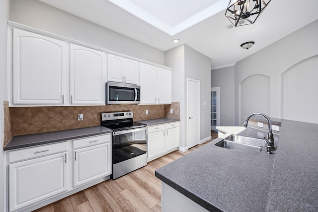 kitchen with dark countertops, light wood-style flooring, a sink, and appliances with stainless steel finishes