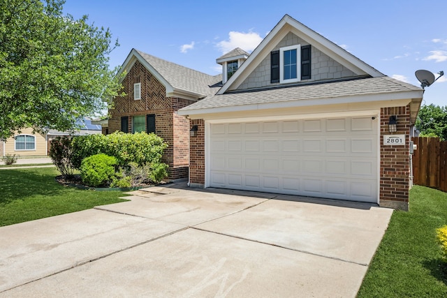 view of front facade with driveway, a shingled roof, fence, a front yard, and brick siding