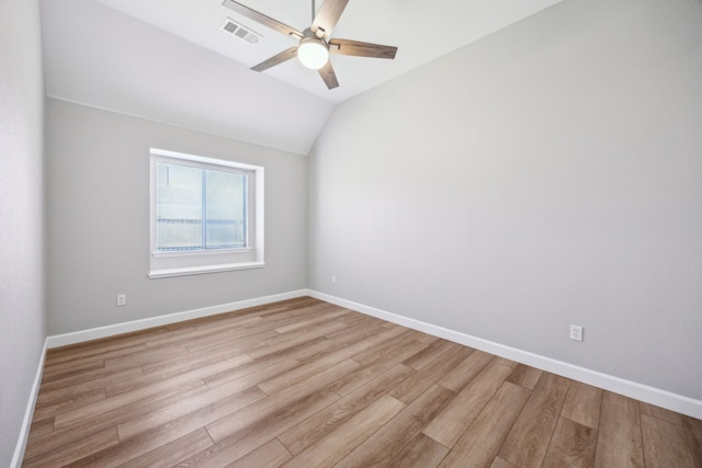 spare room with lofted ceiling, visible vents, a ceiling fan, light wood-type flooring, and baseboards