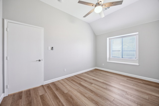 spare room featuring wood finished floors, lofted ceiling, baseboards, and a ceiling fan