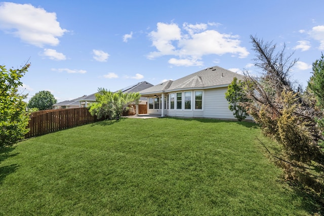 rear view of property featuring a fenced backyard, a patio area, and a lawn