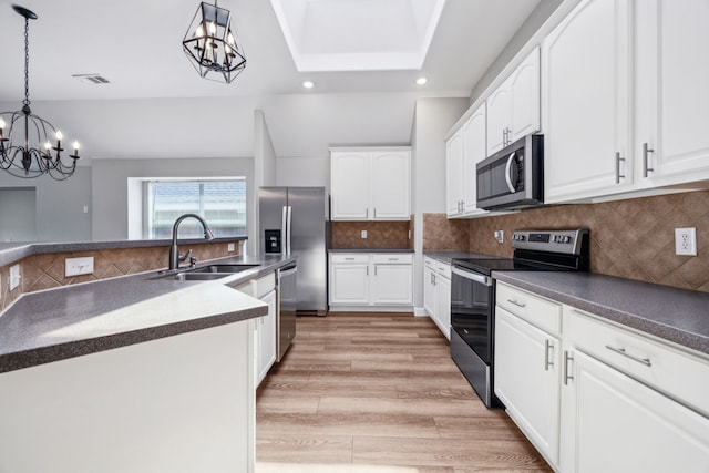 kitchen with dark countertops, a sink, an inviting chandelier, stainless steel appliances, and decorative light fixtures