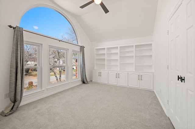 unfurnished room featuring ceiling fan, light colored carpet, built in shelves, and high vaulted ceiling