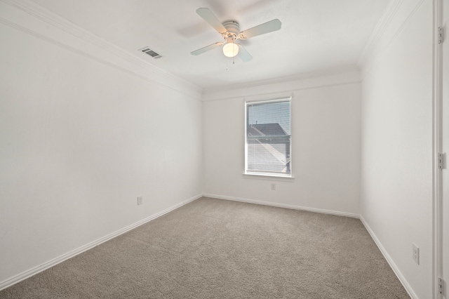 carpeted empty room with visible vents, baseboards, crown molding, and ceiling fan