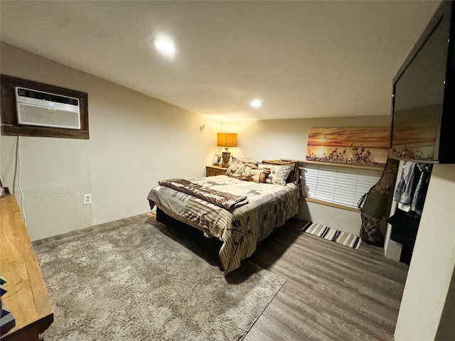 bedroom featuring an AC wall unit, recessed lighting, and wood finished floors