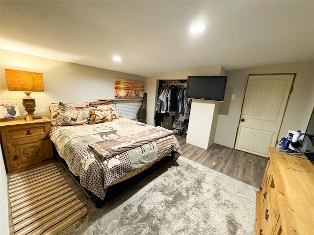 bedroom with recessed lighting, vaulted ceiling, wood finished floors, and a closet