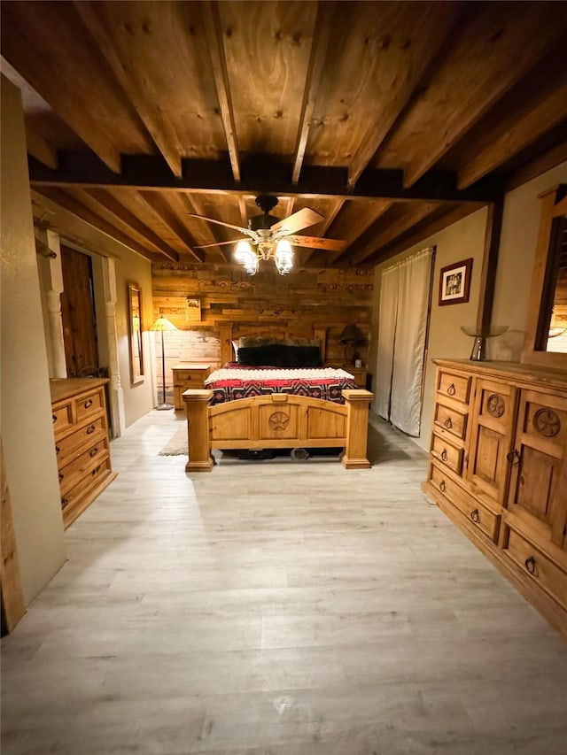 bedroom with beamed ceiling, wood walls, wooden ceiling, and light wood-style floors
