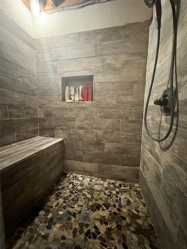 bathroom featuring stone flooring and tiled shower