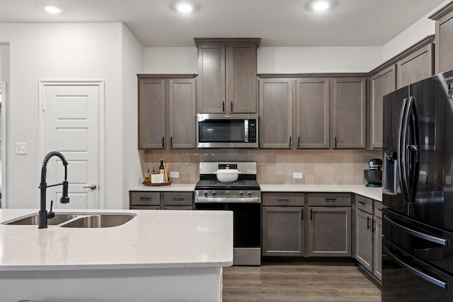 kitchen with stainless steel appliances, dark brown cabinetry, tasteful backsplash, and dark wood finished floors