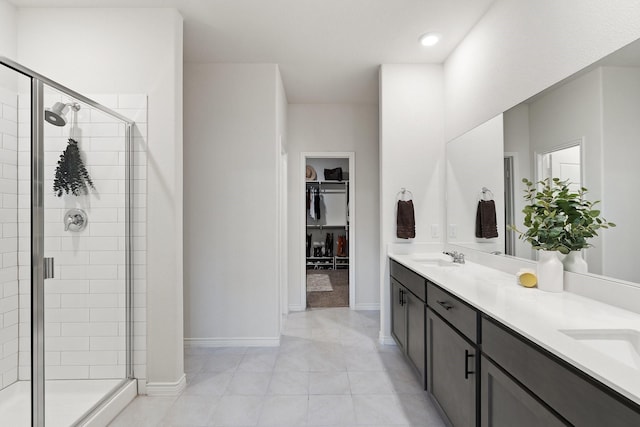 bathroom featuring a shower stall, a spacious closet, tile patterned flooring, double vanity, and baseboards