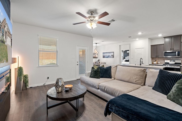 living area featuring a ceiling fan, dark wood finished floors, baseboards, visible vents, and recessed lighting