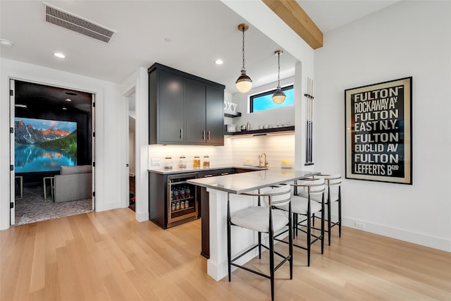 kitchen with open shelves, light wood finished floors, visible vents, a kitchen bar, and wine cooler