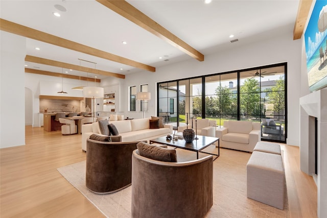 living room featuring a fireplace, recessed lighting, beam ceiling, and light wood-style floors