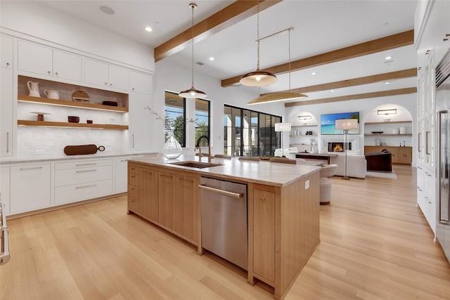 kitchen with beamed ceiling, light wood-type flooring, stainless steel dishwasher, and a sink