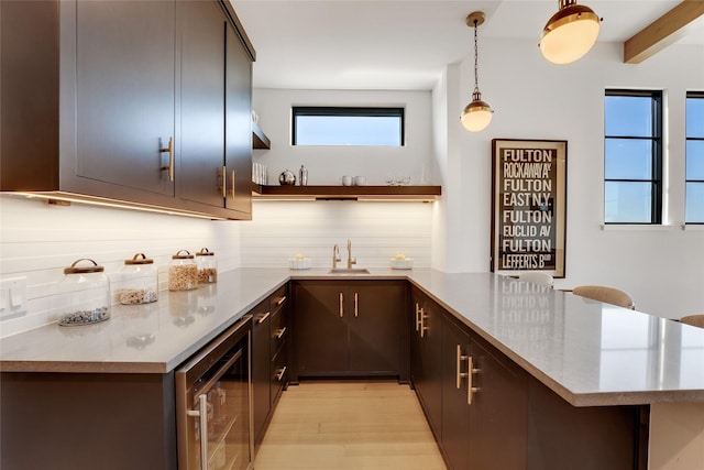 interior space with beverage cooler, wet bar, a sink, pendant lighting, and decorative backsplash