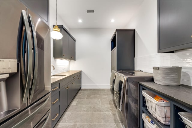 washroom with washing machine and clothes dryer, a sink, baseboards, visible vents, and recessed lighting