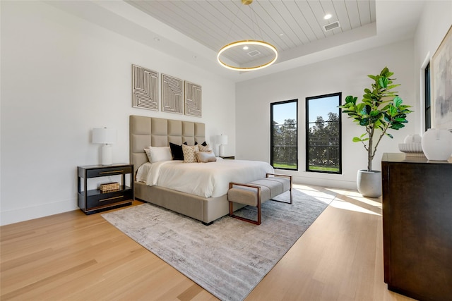 bedroom with a raised ceiling, visible vents, baseboards, wood ceiling, and light wood-style flooring